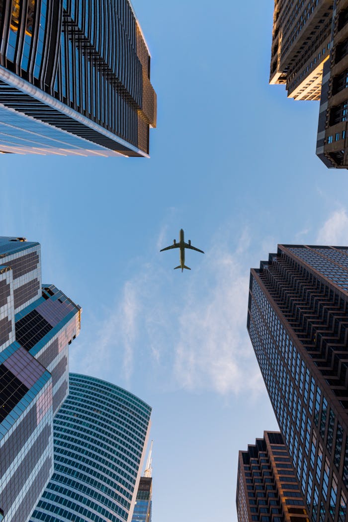 Airplane flies over Chicagos modern skyscrapers against a clear sky, highlighting urban architecture.